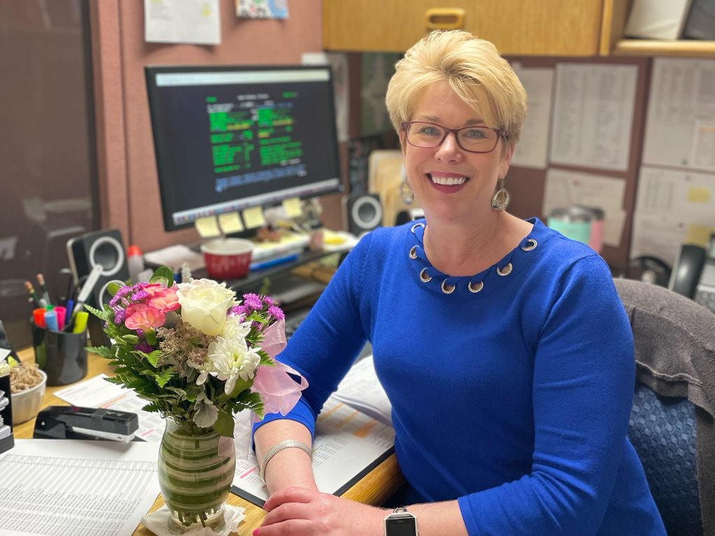 Female employee posing at desk with smile and flowers
